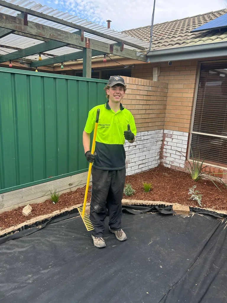Team member giving a thumbs up while preparing a garden bed