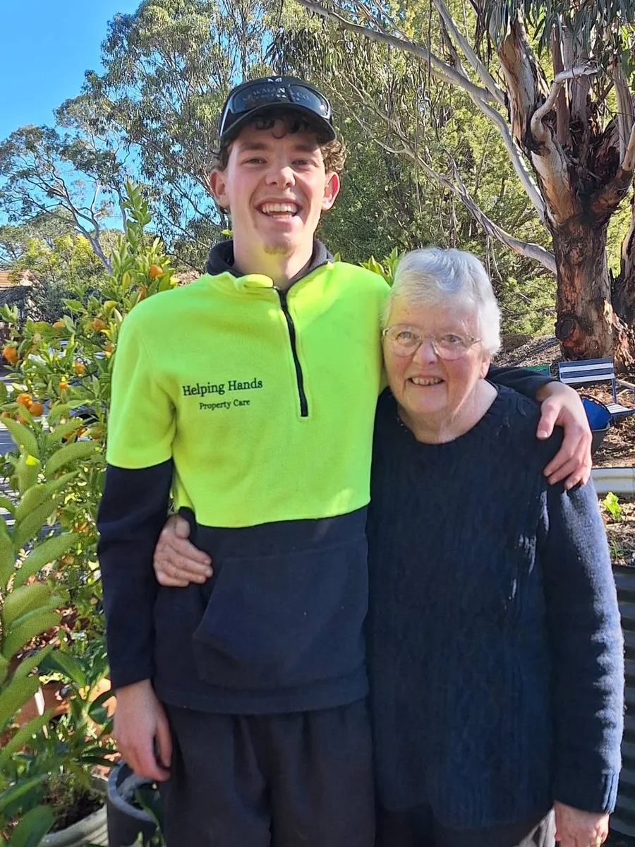 Two people smiling together outdoors beside established planting